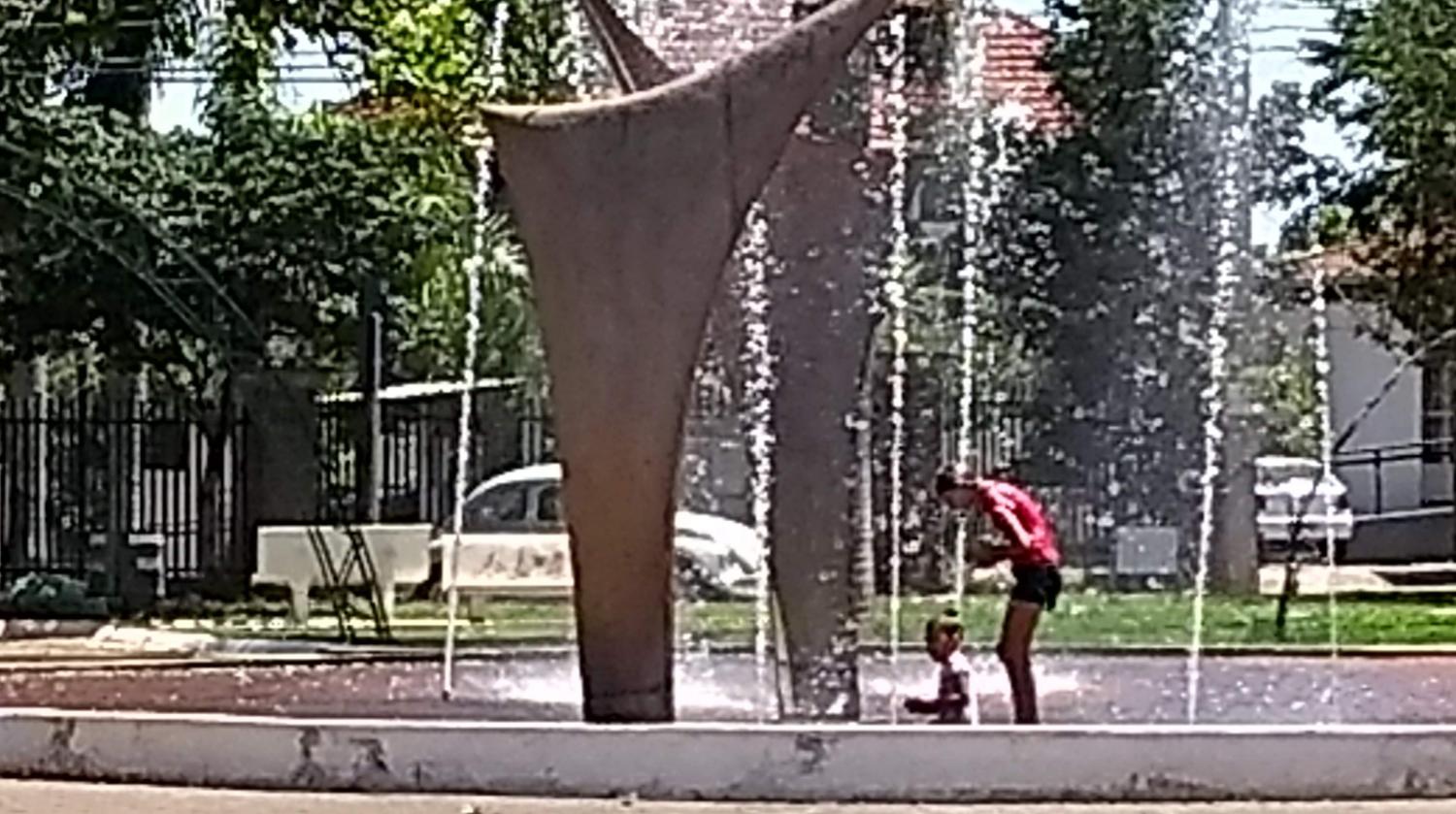 Grupo de crianças utiliza chafariz da praça para tomar banho